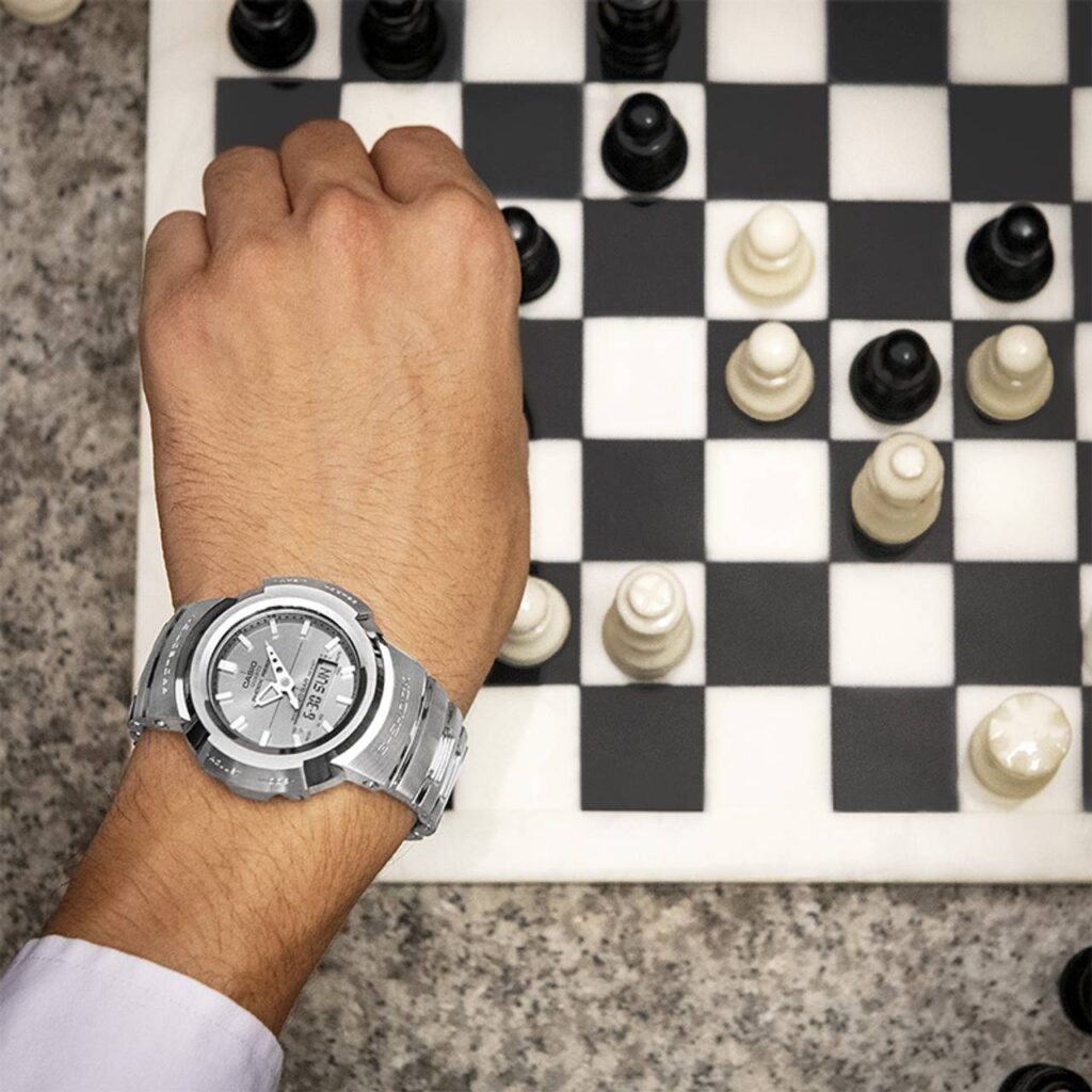 Pessoa realizado movimento do jogo de xadrez onde esta destacando o seu relógio Casio GMW-B5000TVA-1