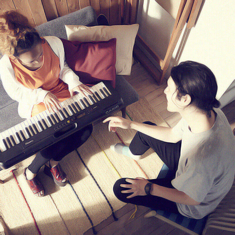 vista de cima de dois amigos tocando teclado e cantando juntos dentro de um sala de estar
